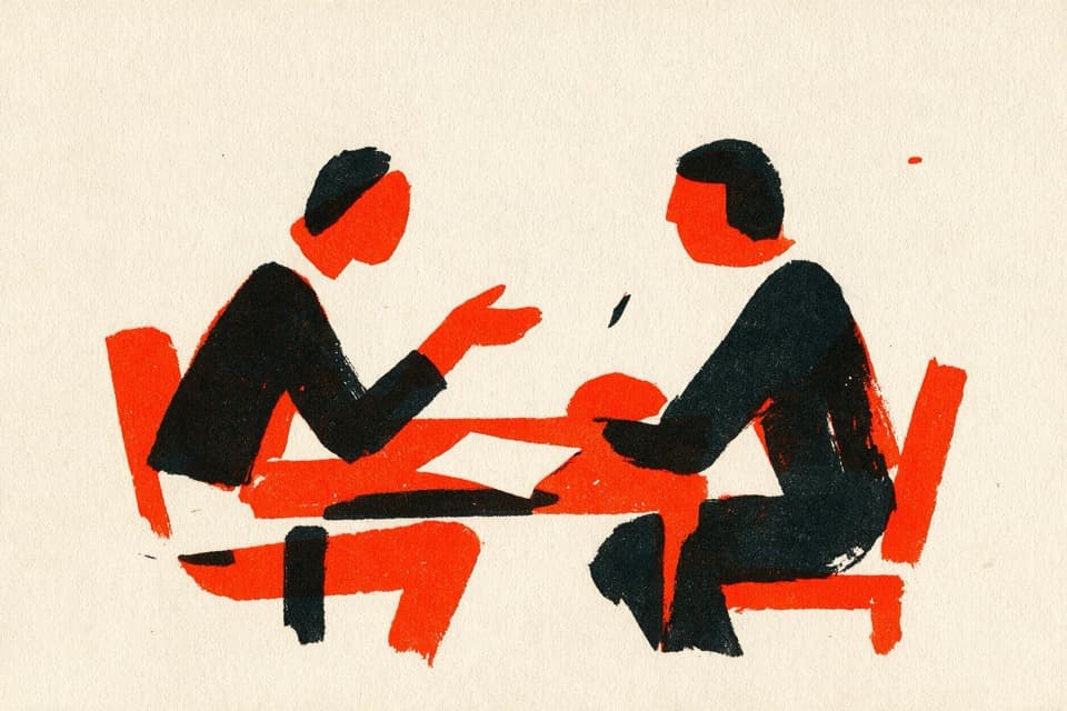 Two figures talking across a table with a single sheet of paper between them